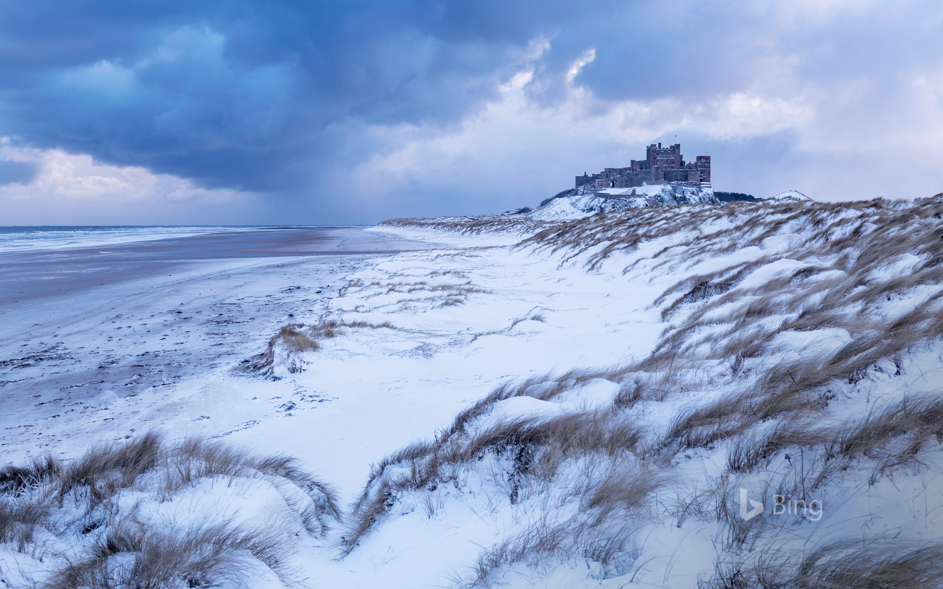 Bamburgh Castle and sand dunes after snowfall in Northumberland