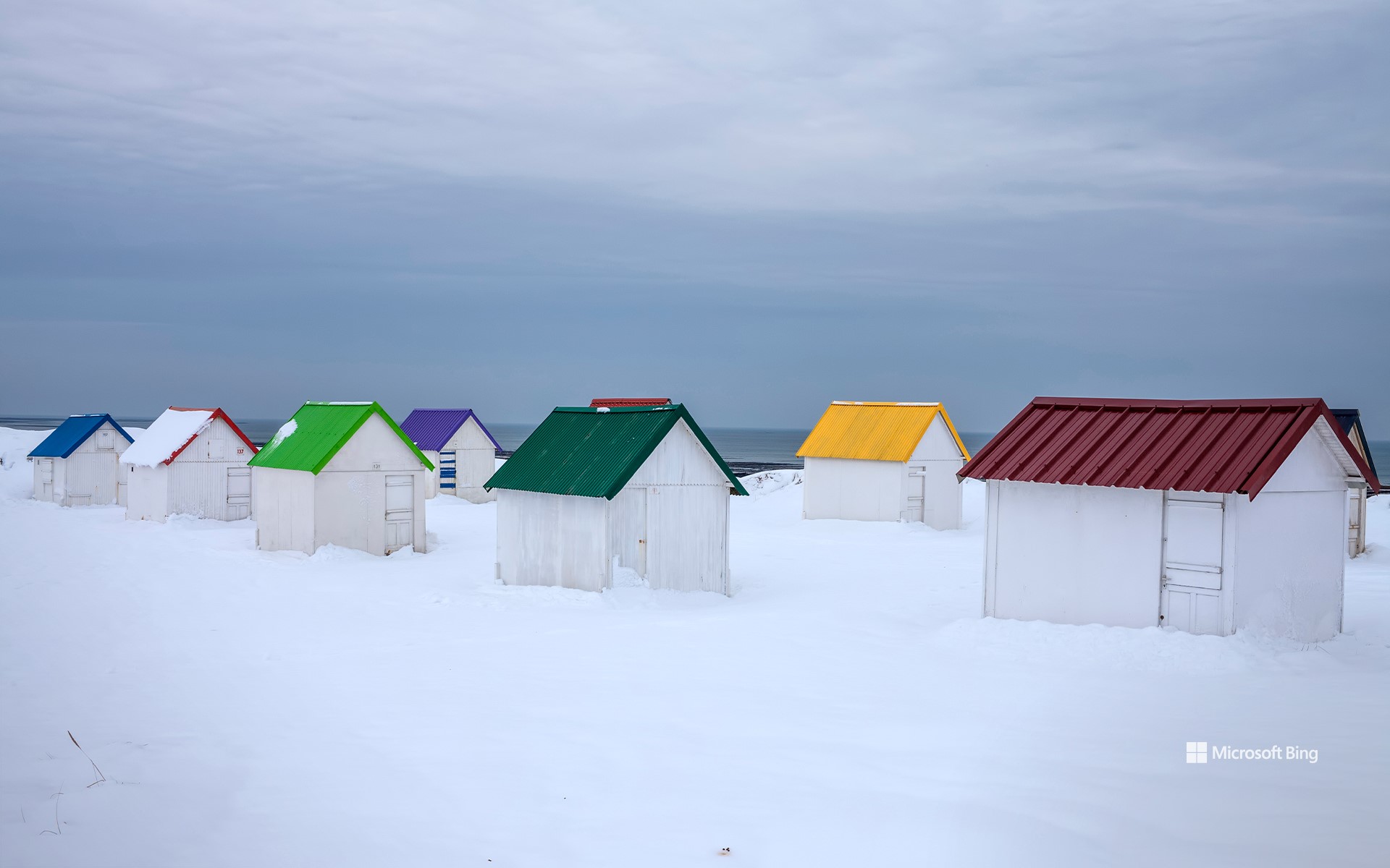 Snow-covered huts with colorful roofs in Gouville-sur-Mer, Normandy