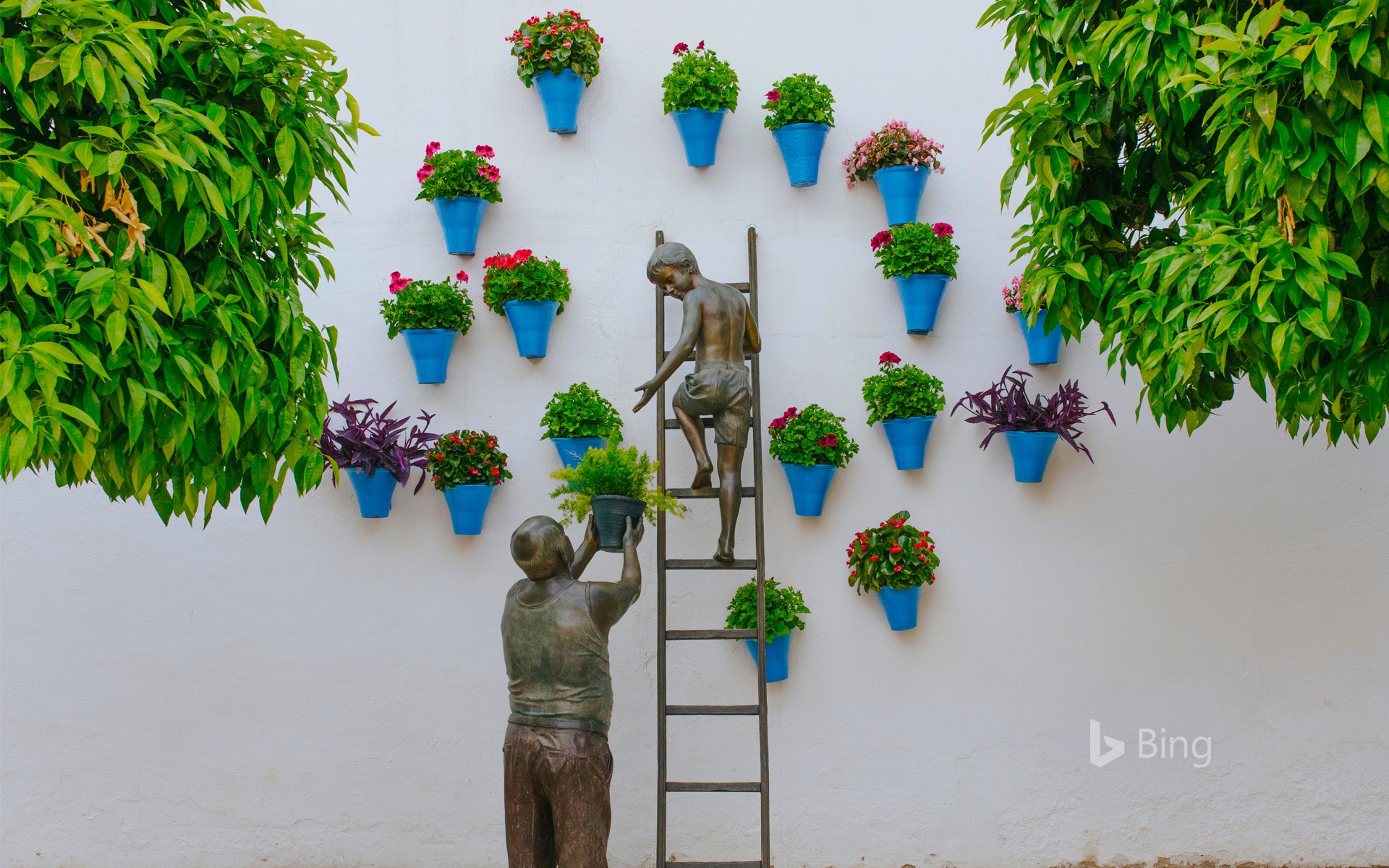 Bronze sculpture of a child and his grandfather caring for plants and flowers in the San Basilio neighborhood of Córdoba, Spain