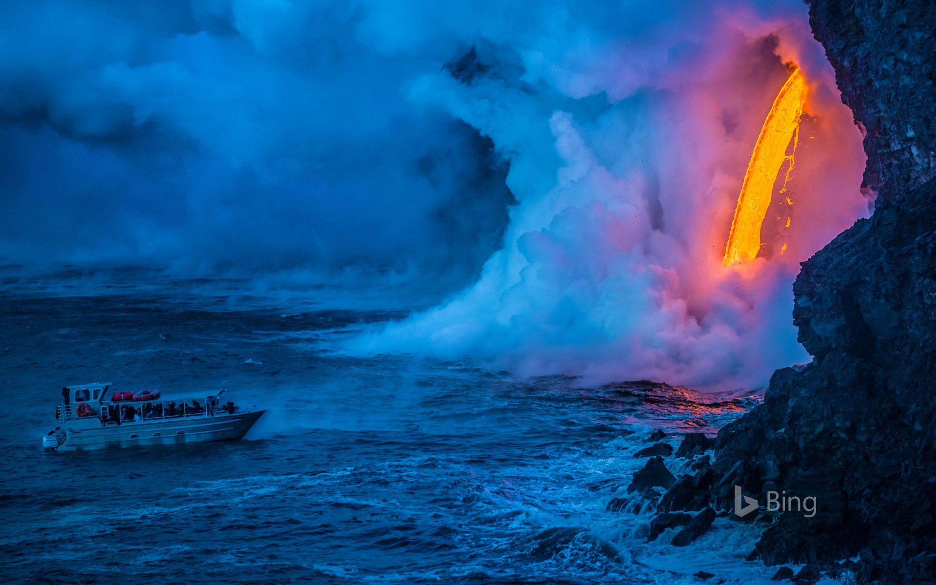 A lava flow hits water to create an explosion as a tourist boat passes, Hawaii Volcanoes National Park, USA