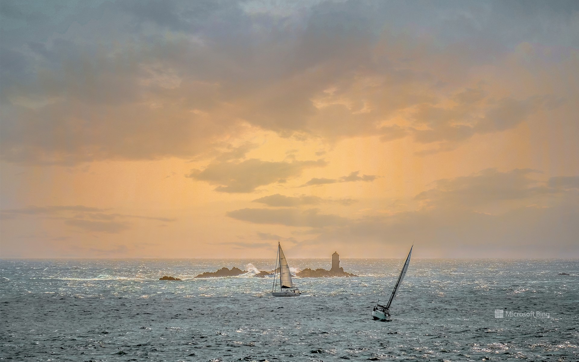 Sailboats at dusk in front of a lighthouse off Roscoff, Finistère, Brittany