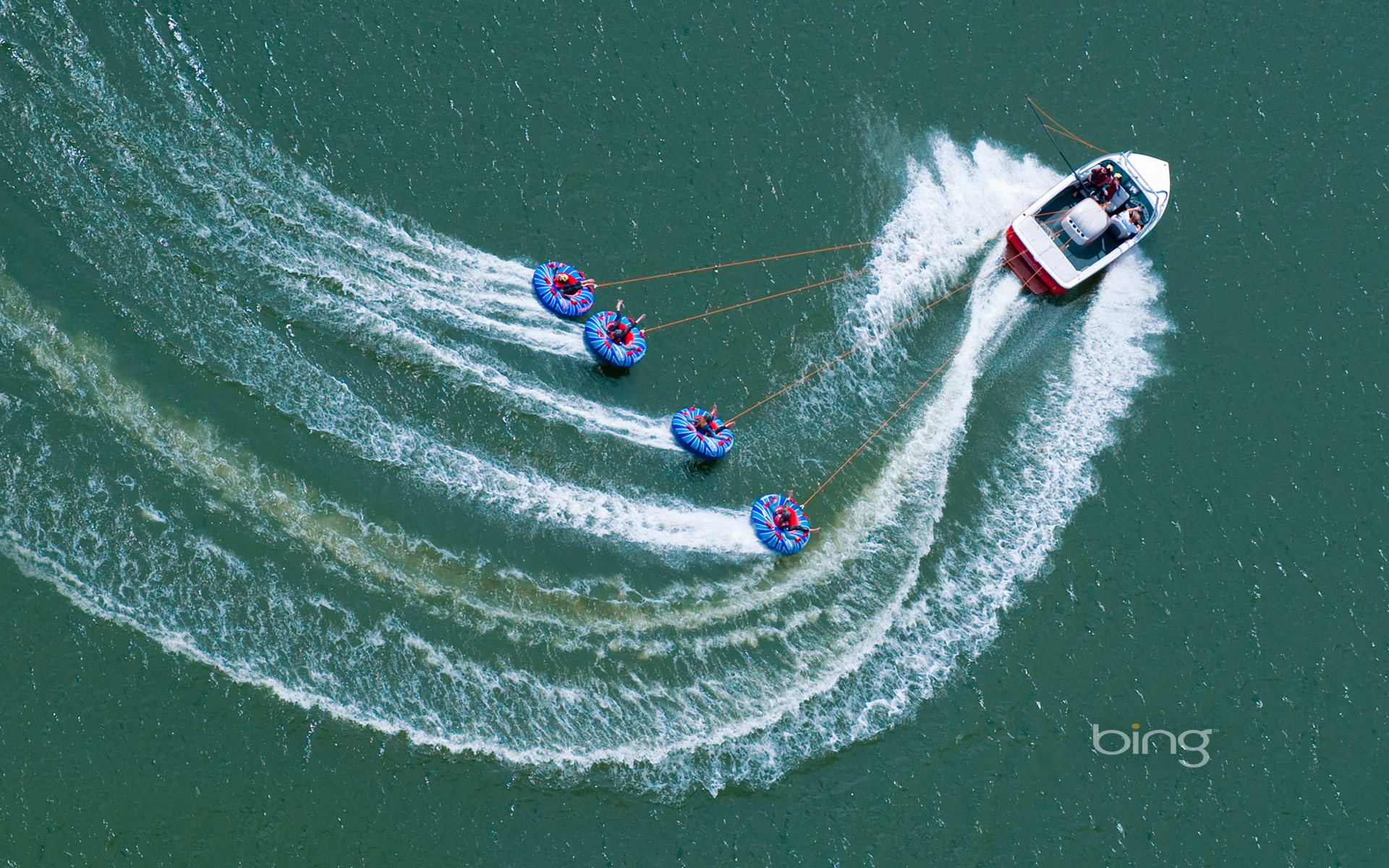 A speedboat tows “tubers” on Abbey Lake in Surrey, England