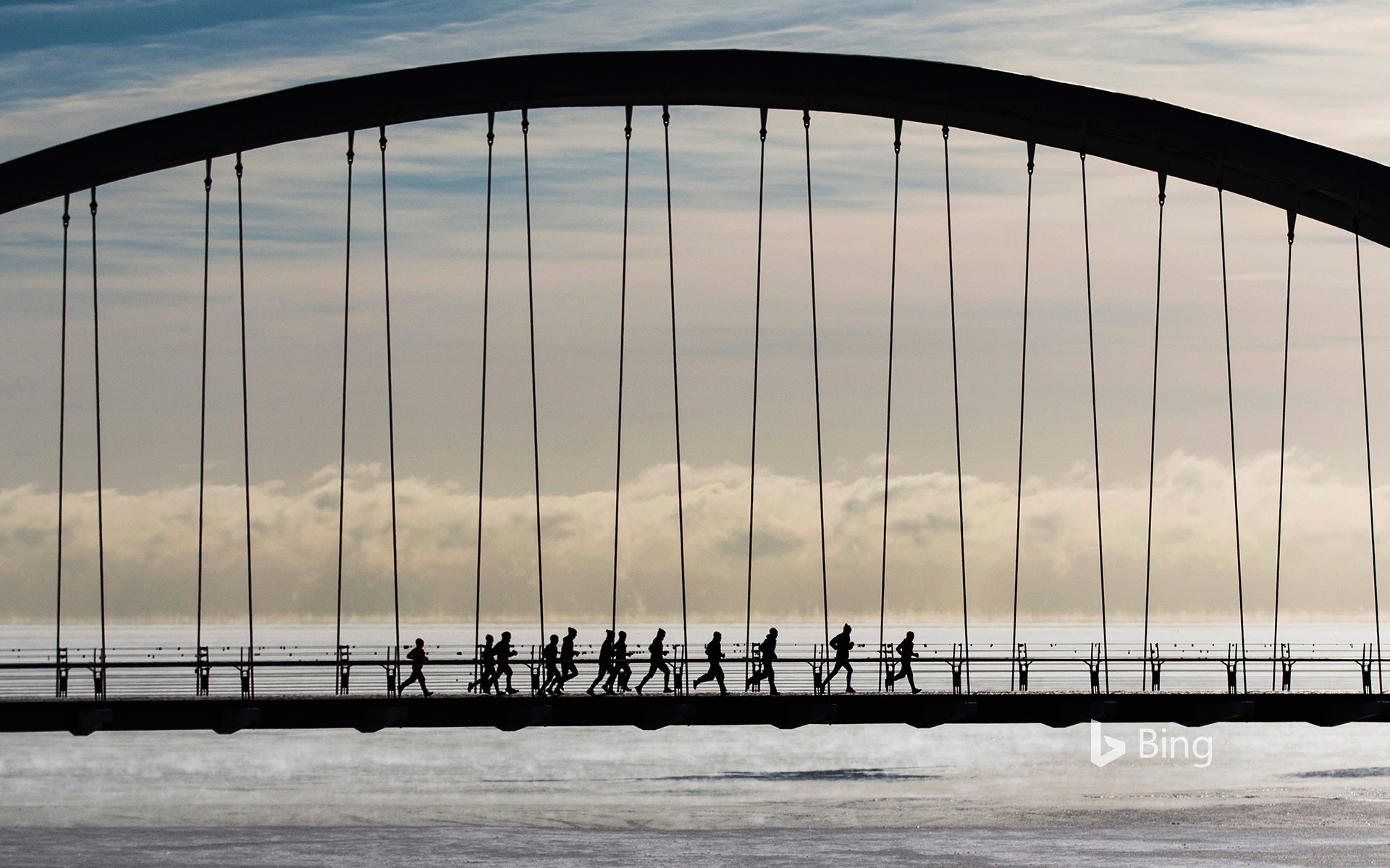 A group of joggers run across the Humber Bay Arch Bridge in Toronto, Canada